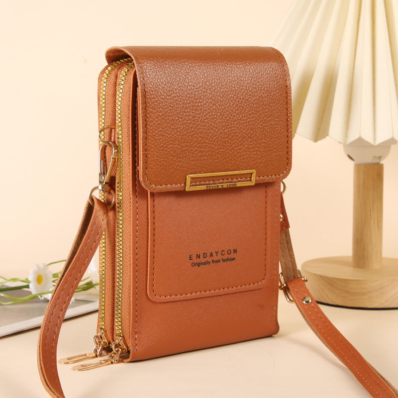 A brown pebbled leather crossbody phone pouch with gold-tone zippers and hardware, featuring the brand name 'ENDAYCON' on the front, set against a warm beige background with a decorative lamp.